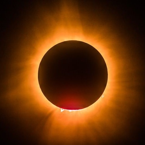 Image shows the totally eclipsed sun centered on the page with the corona in a yellow hue glowing around the dark moon.