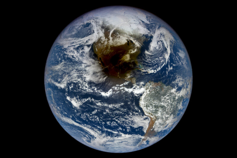 Image shows the sphere of the Earth with the large, brownish shadow of the moon over North America.