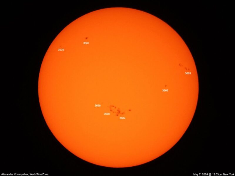 The sun, seen as a large orange sphere with small dark spots.