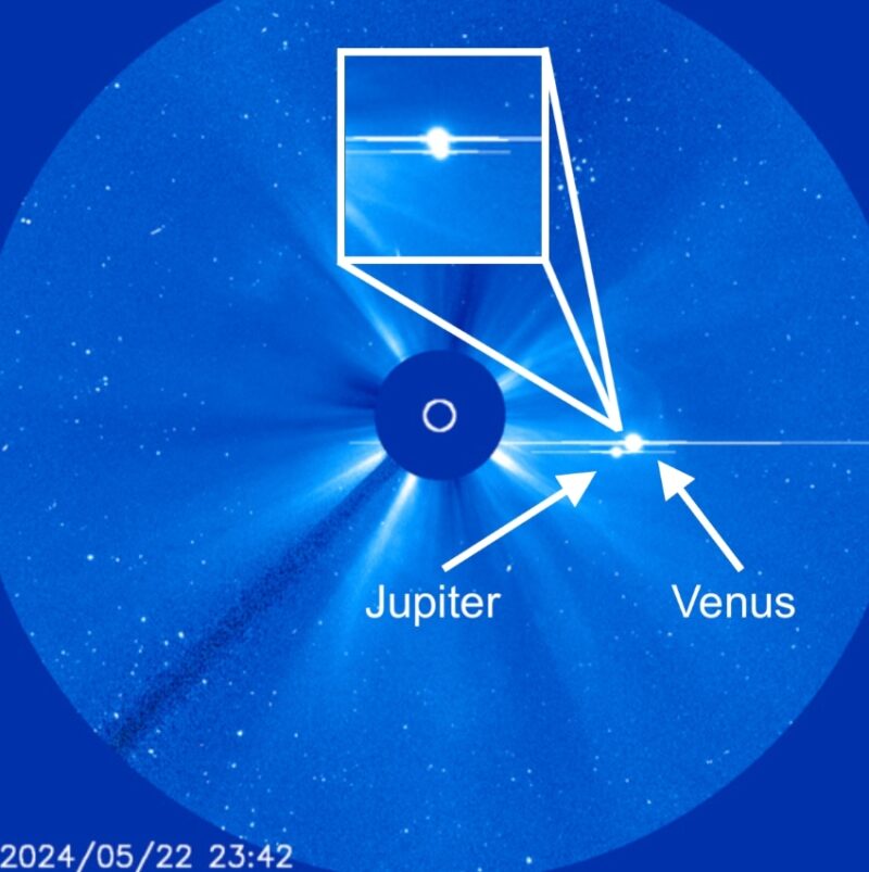 Two bright dots of Jupiter and Venus to the right of a plain blue disk blocking the sun. In the blue background, bright plumes from the sun emerge from behind the plain disk.