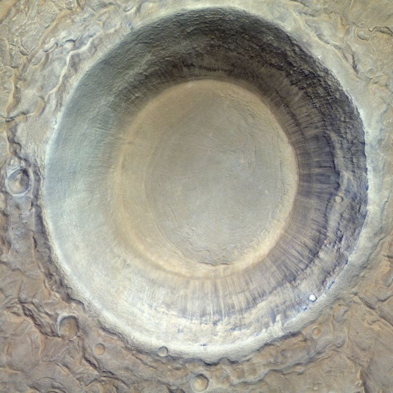 Mars craters: Top-down view at a large crater with steep walls and a smooth floor, all in shades of tan.