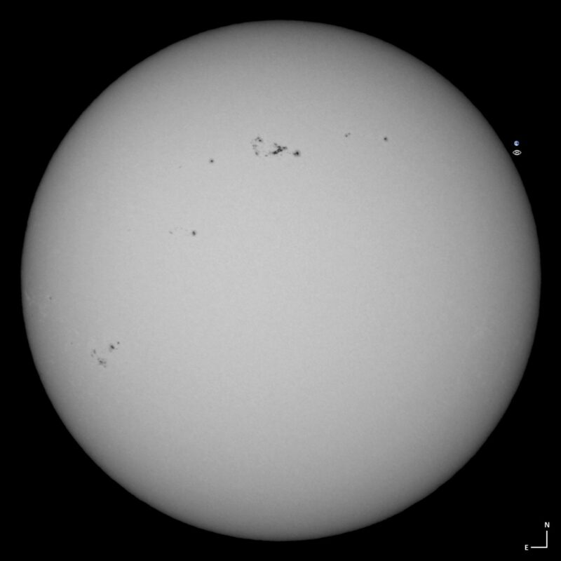 The sun, seen as a large gray sphere with a mottled surface.