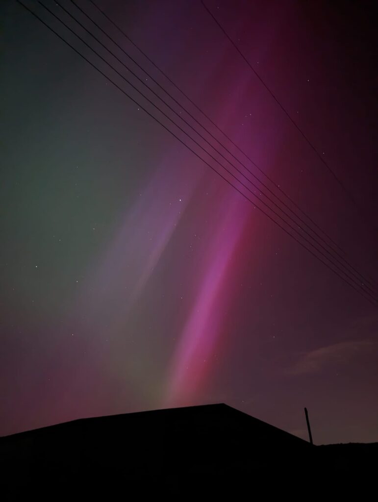 Pink, magenta, and green light stretches diagonally across the sky.