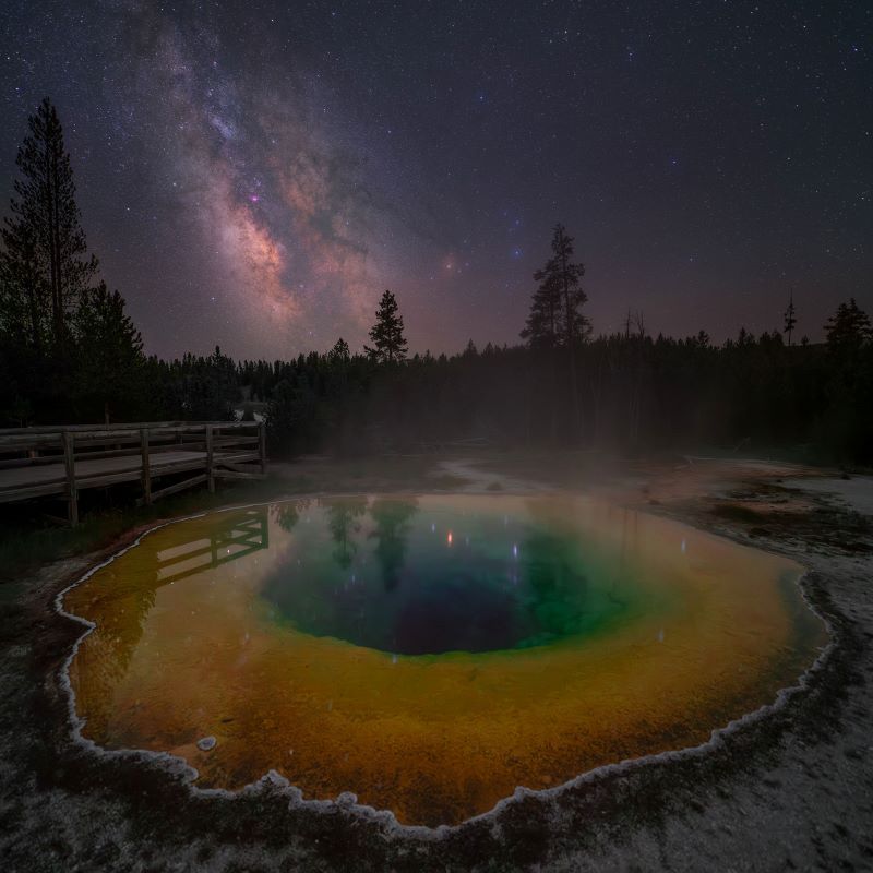 Milky Way glowing in the background and a rainbow colored pool in the foreground.