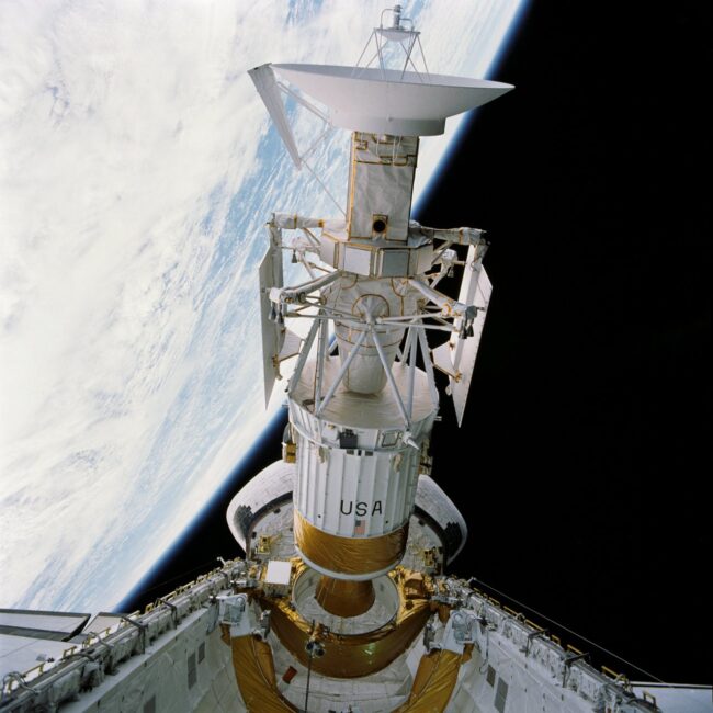 A spacecraft sitting upright in the open bay of a 2nd space vehicle.