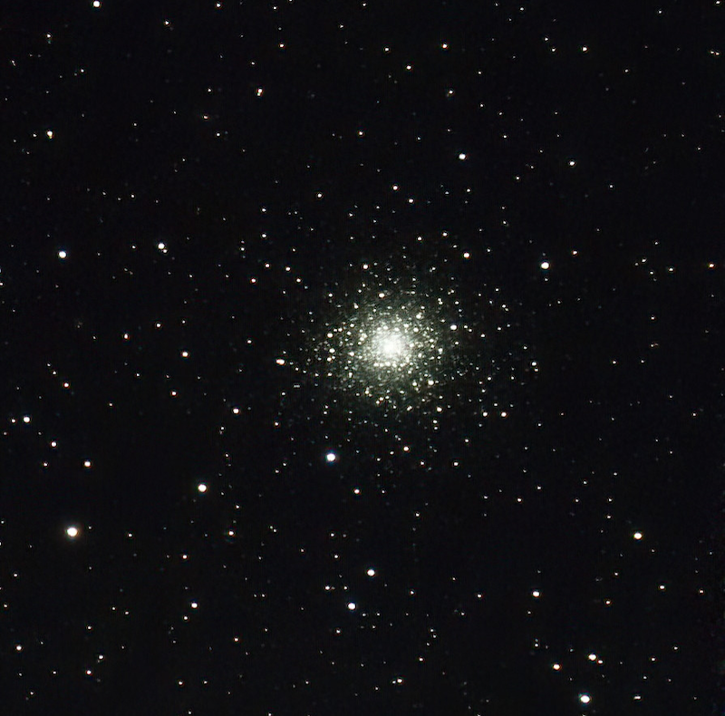 Bright white round cluster of thousands of stars at center in a sparse star field in a black sky.