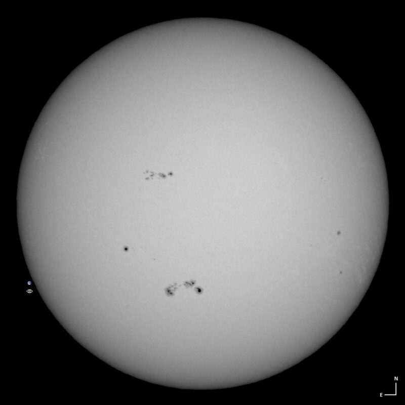 The sun, seen as a large white sphere with small dark spots.