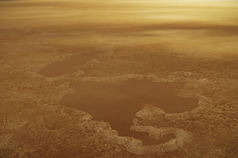 Aerial view of irregular brown lake surrounded by sepia land under a yellow sky.