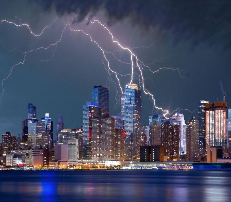Lightning safety: Skyline of a big city at dusk with multiple bolts of lightning coming down from dark clouds.