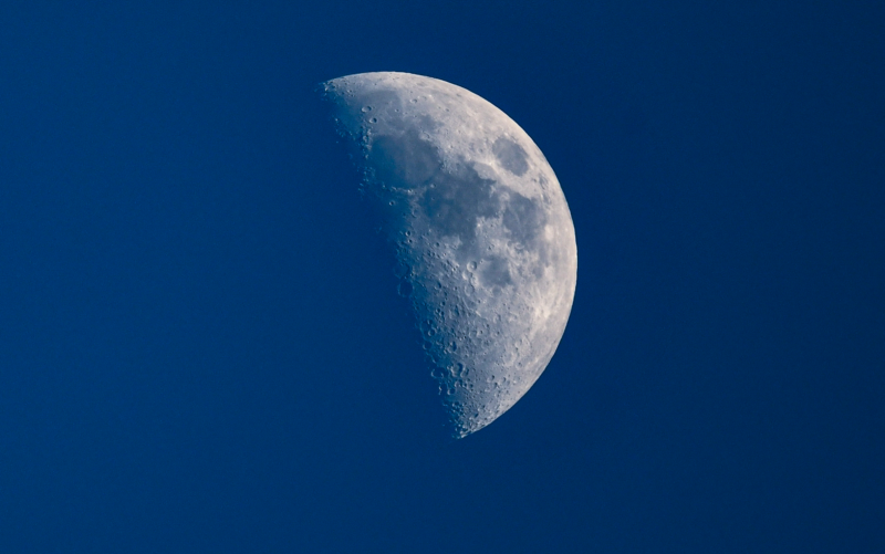 A half-lit moon against a blue background.