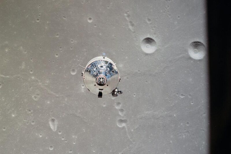 End view of shiny, metallic conical module against light tan lunar surface with craters.