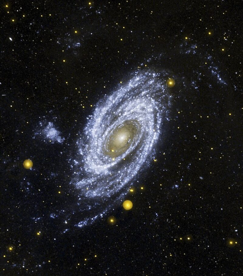 Oblique spiral with yellow center and arms made of thousands of shining pale blue dots.