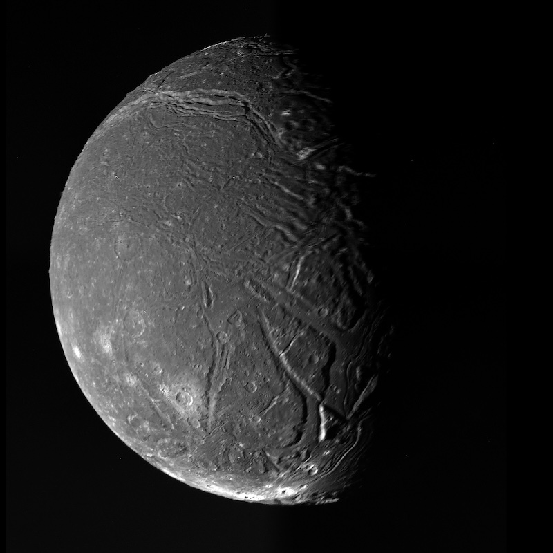 Ariel: A grey rocky lunar sphere with white spots and long, deep cracks on its surface.