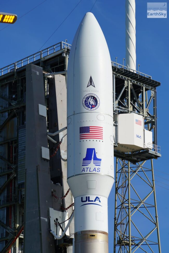 White rocket nosecone and payload with part of rocket extending below still on the launchpad.