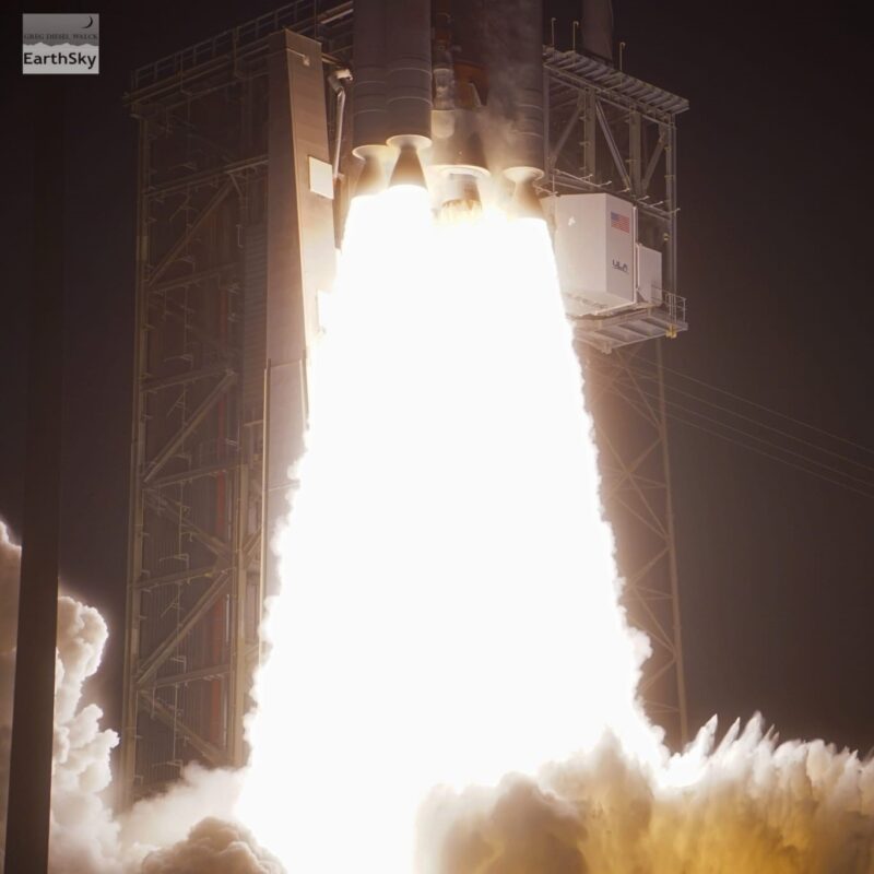 The bottom of a rocket with flames pouring out and smoke starting to billow up.