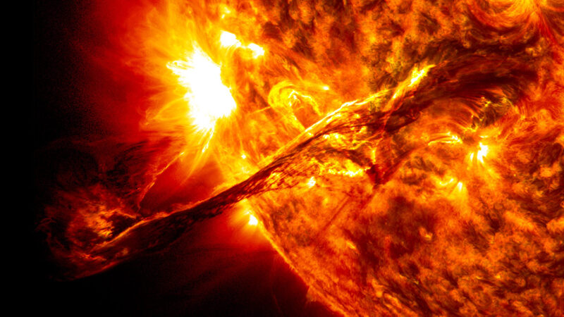 A portion of the sun, with a giant eruption extending out from its surface.