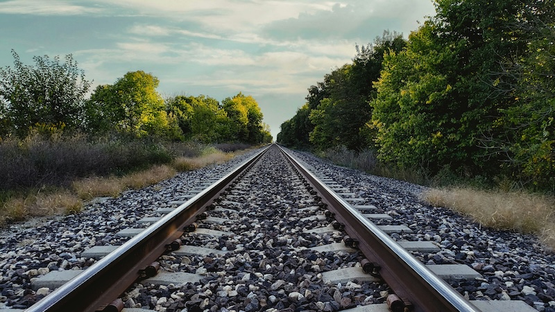 View of train tracks wide apart close to you and close together in the distance.
