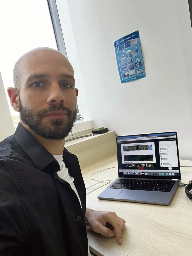 Extreme weather: Man in office posing for camera. Laptop computer on desk.