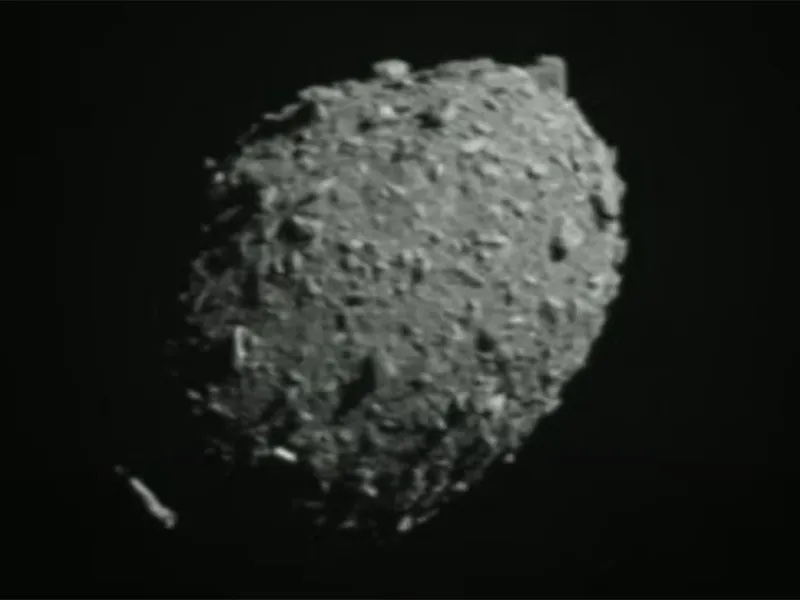 DART mission: Large egg-shaped rocky object with many boulders on its surface, on black background.