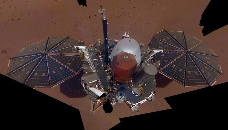 Water on Mars: Complex robot-like machine with 2 large solar panels sitting on reddish sandy terrain, seen from above.