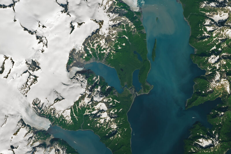 Satellite image of a green landscape with white ice caps and blue water.