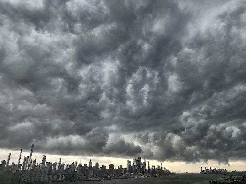 Vast lowering gray clouds over the distant skyline of New York City.