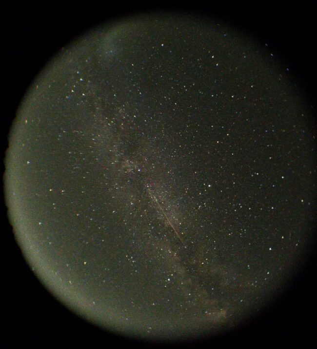 Circle with a starry sky inside. A band of stars and a long streak cross the circle from top lefto to bottom right.