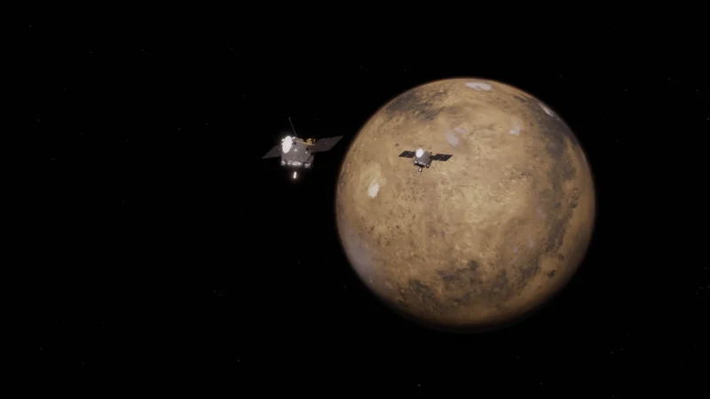 Mars mission: Two metallic cubes with solar panel "wings" fly in front of the sphere of Mars on a black background.