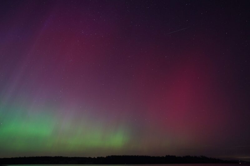 Green lights at bottom left, then turns into purple and then into pink. A faint streak at the top right.