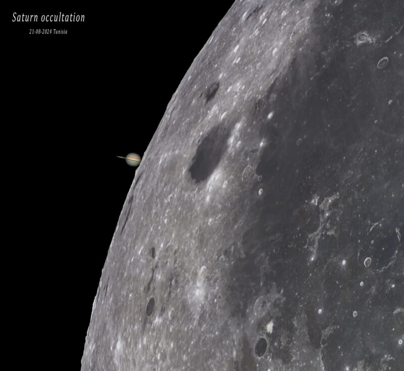 Top left of a gray sphere with some dark gray areas. There is a small, brownish sphere to its left that has a ring around.