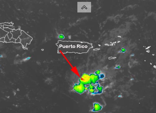 Satellite view of Puerto Rico with an arrow pointing to colorful blotches over the dark sea south of it.