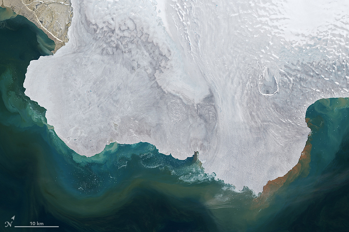 Satellite view of an ice cap with shades of blue swirling off into the surrounding water.