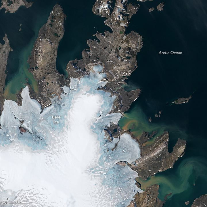 Satellite view of island with rocky protrusions into the sea with the ice noticeably thinner at the edges.