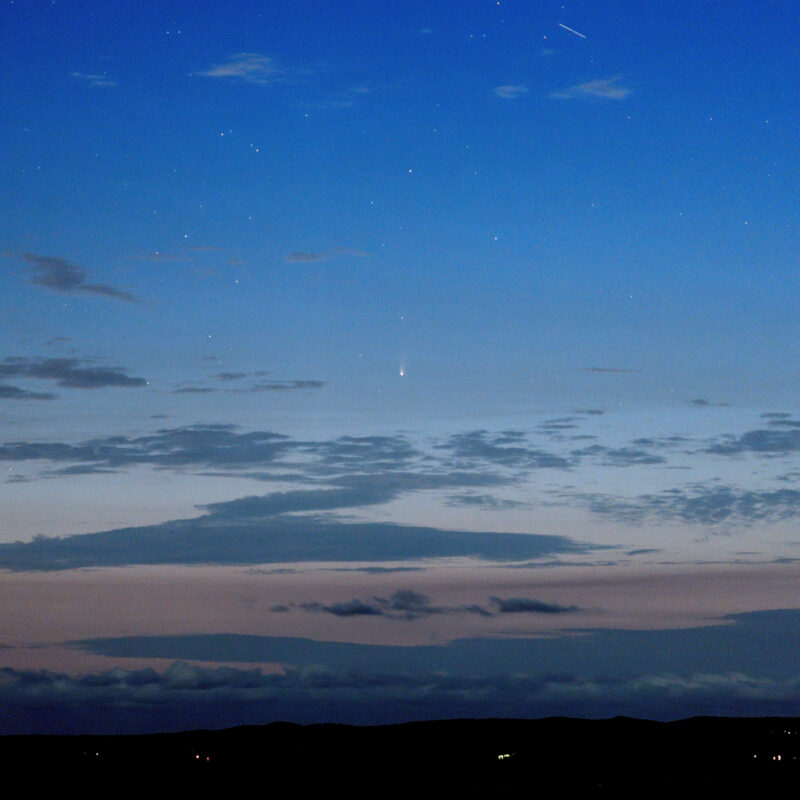 Comet in a sunset sky with tail pointing up.