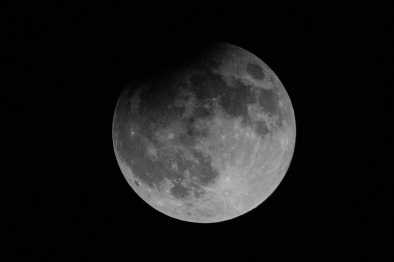 A full moon with a darkened spot at upper left.