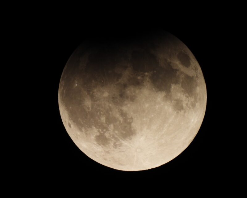 Full moon with darkened region at top.