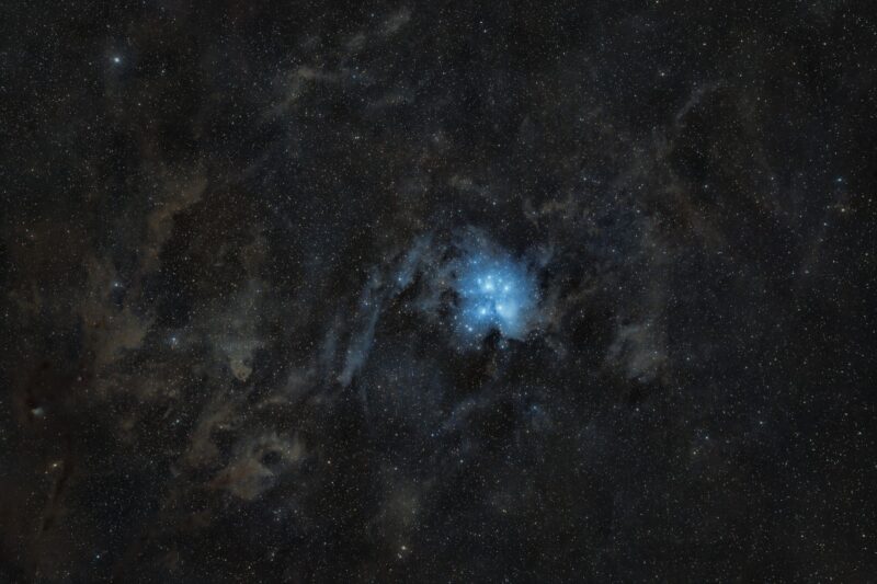 A small area of electric blue nebulosity with bright white stars immersed within.