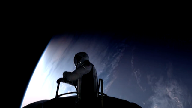 Silhouette of an astronaut going out of the top of a round spacecraft. Blue Earth with some shite clouds in the background.