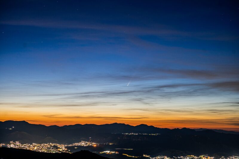 Sunrise colors with a comet appearing through thin clouds.