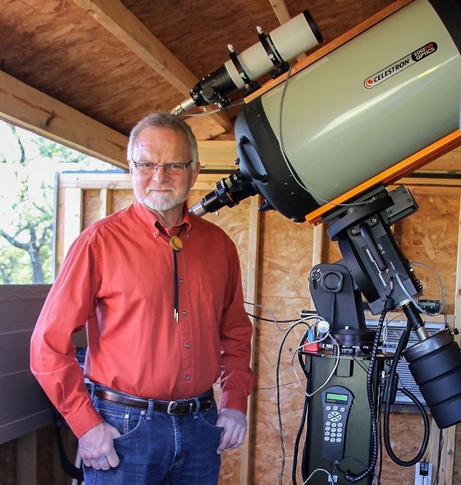 Moon expert Robert Reeves, a white man with glasses, standing to the left of a large, complex home telescope.