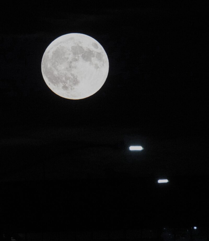 A full moon with little oblongs of light to the lower right.