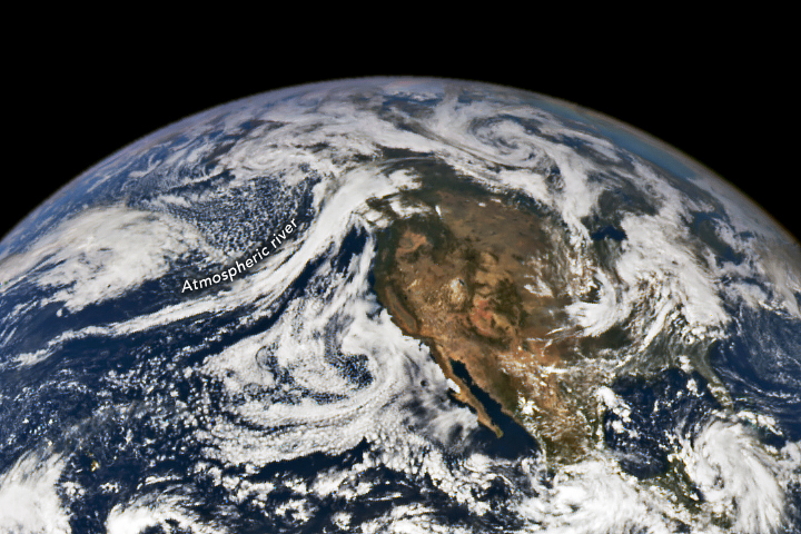 Satellite view with a big mass of land and many white clouds around. One long, thin cloud has the label "Aatmospheric river".