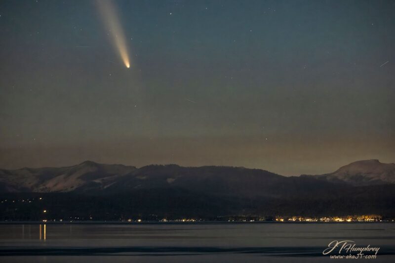 The comet over a mountain range and body of water.