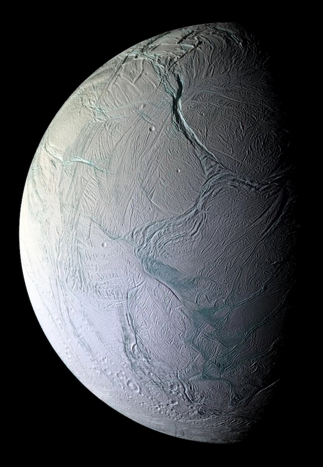 Planet-like body with long curving cracks on its surface. Half of it is illuminated by sunlight.