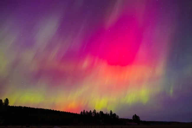 A sky filled with an extremely vivid aurora, mainly magenta with green at the bottom.