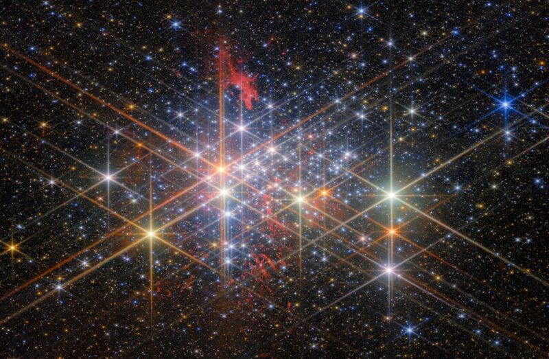 A dense cluster of very many bright multicolored stars with rays coming out.