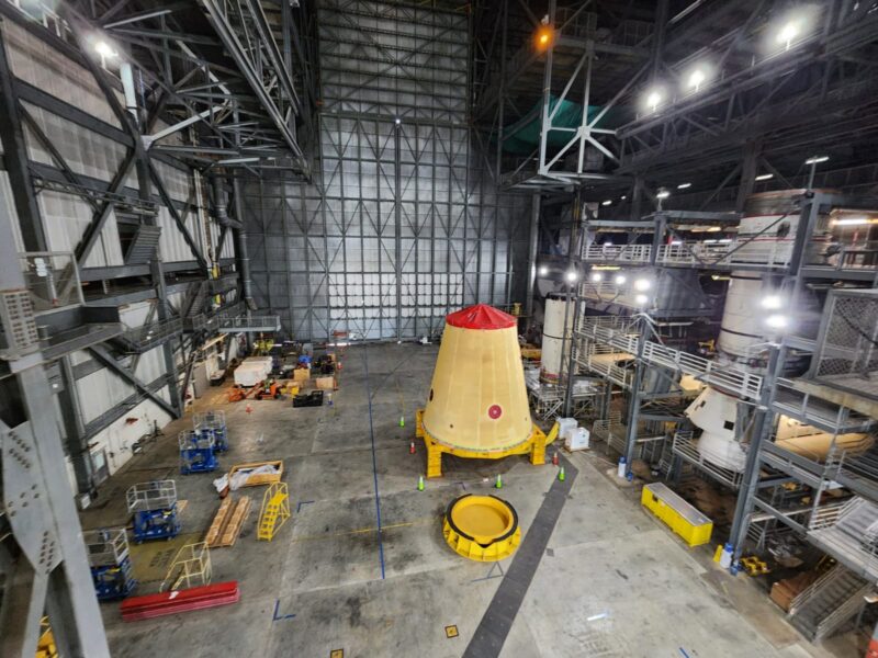 Huge, brightly lit enclosed workshop with a yellow cone with a red top sitting upright on the floor.