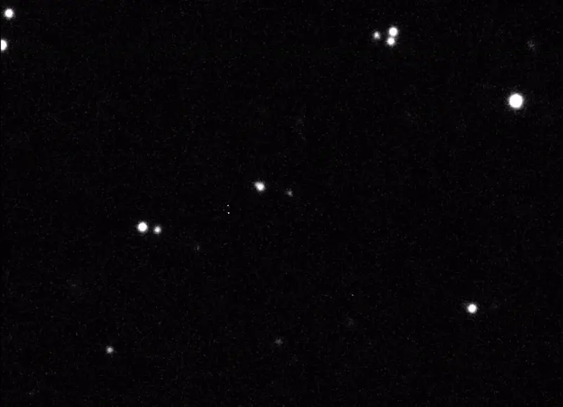 White dots of stars move together across a black background, while a fainter white dot in the middle - asteroid 2024 YR4 - remains still.