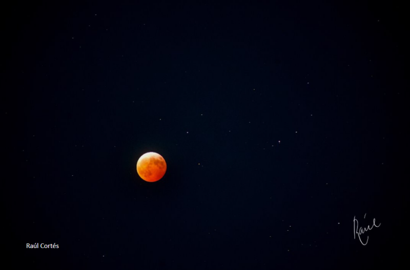 Orange moon in a dark background with many dim stars around.