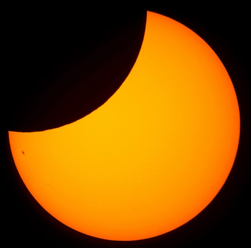 Eclipse: The sun, seen as a large yellow crescent with small dark spots.